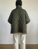 Poncho acolchado color vino tinto, con cuello alto y cierre frontal parcial. Presenta un patrón de costuras capitoné en forma de hoja o diamante y bolsillos delanteros.
