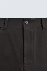 Pantalón chino regular fit de color negro, confeccionado en tejido de algodón. Cuenta con bolsillos frontales, detalle de bolsillo cerillero, bolsillos traseros de doble vivo y cierre frontal con cremallera y botón.