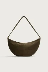 Bolso de hombro de diseño medialuna, confeccionado en piel con acabado de serraje. Cuenta con un compartimento principal con cierre de cremallera y un bolsillo interior con cierre. Incluye asa fija para llevar al hombro.