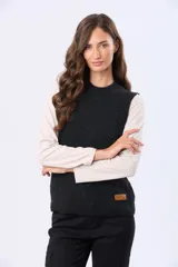 Chaleco tejido color negro, con cuello alto y diseño de trenzas en el frente. Tiene un parche de cuero sintético marrón con logo en el dobladillo inferior.