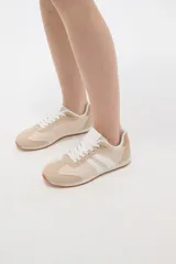 Zapatillas de estilo urbano color marrón con detalles en blanco, confeccionadas en material textil y sintético, con cordones blancos y suela de goma.