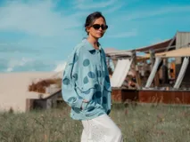 Campera celeste con lunares grandes color azul marino, con cuello camisero, cierre con botones a presión, bolsillos frontales con solapa y corte holgado.