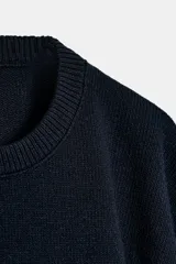 Jersey de punto con cuello redondo y mangas anchas tipo murciélago. Presenta un diseño de corte holgado con terminaciones en rib a tono en el cuello, puños y bajo.