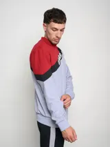 Buzo de hombre con diseño de bloques de color, combinando rojo en la parte superior de los hombros y gris melange en el cuerpo. Presenta una franja diagonal negra con el logo Umbro en blanco cruzando el pecho.