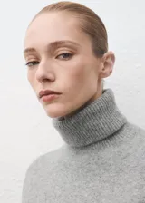 Vestido corto de punto color gris, de corte recto, con cuello vuelto y manga larga.