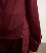 Campera deportiva femenina, modelo rompevientos, confeccionada en poliamida, con cuello alto y puños ajustados. Sin estampa, tiene cierre delantero con cremallera y recortes con hilo reflectante.