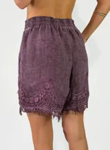 Short de lino color violeta con detalles de encaje bordado en el ruedo.