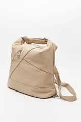Cartera convertible en mochila, confeccionada en cuero sintético texturizado color marrón. Presenta un diseño con recortes, bolsillo frontal con cierre diagonal, herrajes metálicos plateados, asa superior y correas regulables.