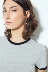 Remera cropped blanca de manga corta, con cuello redondo y terminaciones en contraste de color marrón en cuello y mangas. Inspirada en los clásicos de los años 80.