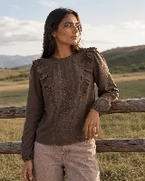 Blusa de manga larga color marrón, con escote redondo, detalle de volados en los hombros y bordado floral en la parte delantera.