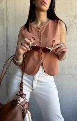 Chaleco color terracota con botones frontales y corte irregular en el ruedo. Sin mangas y con cuello redondo.