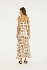 Vestido largo con estampado de caracoles y estrellas de mar, escote recto y tirantes finos. Cuerpo de algodón con forro y falda plisada de tejido liviano semitraslúcido.