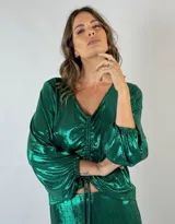 Blusa verde esmeralda metalizada con escote en V, mangas largas abullonadas y fruncido central con lazos ajustables.