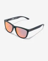 Gafas de sol unisex Hawkers edición limitada Alex Rins, con montura cuadrada negra con textura de fibra de carbono y lentes polarizadas color naranja.