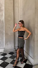 Falda asimétrica de tejido lurex negro y dorado, con pretina elástica y apliques de crochet en el ruedo.