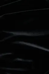 Vestido corto entallado de terciopelo negro, con escote redondo y mangas cortas. Presenta un diseño con pliegues laterales que crean un efecto drapeado en el frente.