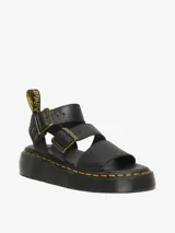 Sandalia Dr. Martens Gryphon Quad negra con plataforma, fabricada con piel Pisa. Presenta tres correas ajustables con hebillas de latón, pespuntes amarillos distintivos en la suela y tirador trasero con el logo AirWair.