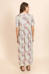 Vestido largo con estampado de hojas en tonos verde, rojo y blanco, con escote en V y botones frontales.