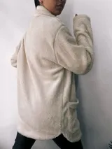 Saco de abrigo color crudo, de corte recto y largo a la cadera, confeccionado en tejido tipo teddy con cuello solapa y cierre frontal con botones.