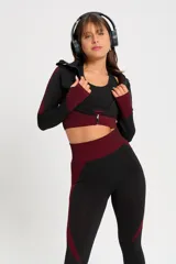 Conjunto deportivo de tres piezas compuesto por un top, una calza chupín de tiro alto y una campera corta con cierre frontal. El diseño presenta una combinación de texturas en color negro y detalles en bordó.