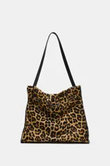 Bolso de hombro confeccionado en piel con estampado animal print de leopardo y textura. Cuenta con compartimento interior con cremallera, asa larga de hombro y cierre mediante botón imantado.