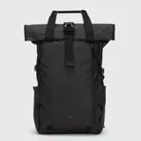 Mochila urbana de diseño moderno con cierre superior enrollable (roll-top) y hebilla de seguridad. Cuenta con compartimento principal, acceso posterior para computadora, bolsillos laterales y correas ajustables. Presenta un acabado liso en color negro con detalle de logo minimalista en la parte inferior.