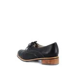 Zapato tipo Oxford de cuero negro con calados y costuras en contraste. Tiene cordones de algodón, suela de goma antideslizante y taco foliado de 2 cm.
