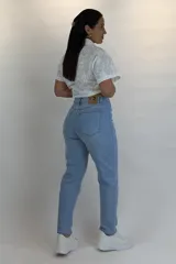 Jean mom fit de color celeste claro, tiro alto, con cinco bolsillos y cierre frontal con botón y cremallera.
