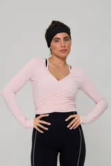 Top deportivo de manga larga en color rosa claro, con diseño cruzado tipo ballet y escote en V. Confeccionado en tejido elástico y ligero.