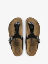 Sandalias Birkenstock modelo Gizeh, color negro charol, con tira delantera ajustable con hebilla metálica y plantilla anatómica de corcho y látex.