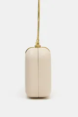 Bolso tipo clutch rígido de mano, color beige, con detalle de apliques metálicos dorados en el frente y cierre mediante clip. Incluye cadena extraíble para usar como bandolera.