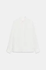 Camisa de cuello solapa y manga larga, con cierre frontal de botones y bajo asimétrico.