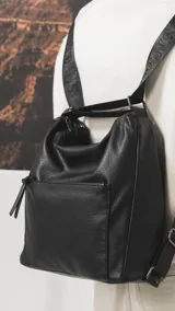 Cartera convertible en mochila de diseño versátil, color tostado, con textura granulada. Cuenta con un bolsillo frontal con cierre, compartimento principal espacioso y correas ajustables para llevar al hombro o como mochila.