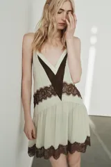 Vestido corto de tirantes finos ajustables con escote en pico. Presenta un diseño en color crema con detalles de encaje en color marrón a contraste en el escote, la cintura y el ruedo. Incluye forro interior.