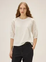 Remera color tiza, de corte clásico con escote a la base, cuerpo de algodón y mangas raglán de broderie.