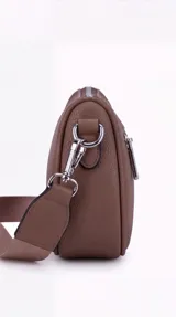 Bandolera de cuero sintético negro con diseño estructurado, múltiples bolsillos con cierre, correa ancha ajustable y herrajes metálicos plateados.