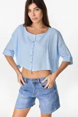 Camisa de lino azul marino, de corte crop y holgado, con cuello redondo, botonadura frontal y mangas amplias con vuelta.