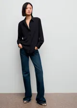 Camisa básica de tejido fluido y color negro, con diseño recto, cuello camisero, manga larga con puños abotonados y cierre delantero con botones.