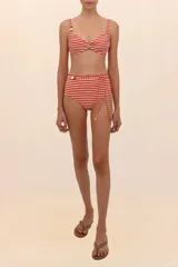 Top de bikini estilo corsetero con estampado a rayas horizontales rojas y blancas, con tirantes finos y cuentas decorativas en el escote.