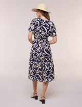 Vestido midi azul marino con estampado floral grande en color beige, escote en V con cuello mao, mangas cortas, cintura fruncida con elástico y falda con volados en niveles.
