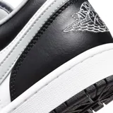 Championes Nike Air Jordan 1 Low, en combinación de colores blanco, negro y gris. Presentan diseño de corte bajo con capellada de cuero, el característico logo swoosh en el lateral, perforaciones en la puntera para mayor transpirabilidad y suela de goma duradera.