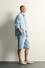Camisa de corte relajado confeccionada en denim ligero de algodón, con cuello solapa, manga larga con puños abotonados y bolsillos de plastrón en el pecho. Presenta un acabado con efecto lavado y cierre frontal mediante botones.