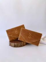 Billetera tipo sobre confeccionada en cuero color camel, con solapa en punta y detalle de costura decorativa en forma de espiga. Cuenta con cierre de broche y monedero externo.