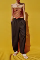 Pantalón de lino marrón oscuro, de corte barrel con pernera holgada que se estrecha hacia el tobillo, cintura elástica y bolsillos delanteros.