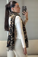 Bufanda rectangular con estampado animal print de leopardo en tonos marrones y negros, con terminación de flecos en los extremos.