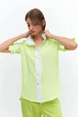 Camisa de manga larga confeccionada en broderie de algodón con bordados en hilo flúo color naranja. Presenta cuello mao, cartera frontal con volados y puños con volados.