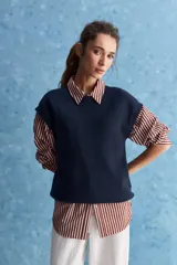Chaleco de tejido de punto color beige claro, con cuello redondo y diseño de líneas limpias con hombros caídos y terminaciones acanaladas.