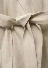 Abrigo largo de lino con diseño recto, cuello con solapas amplias, cierre frontal mediante lazo ajustable en la cintura y mangas largas con puños abotonados.