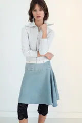 Falda midi de denim en tono azul claro, con tiro medio y diseño asimétrico con tablas laterales. Cuenta con cierre lateral mediante cremallera metálica.