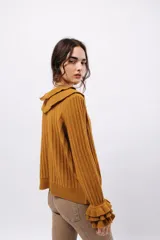 Buzo de tejido acanalado color lila, con cuello redondo decorado con dos volados y mangas largas con tres volados pequeños en los puños.